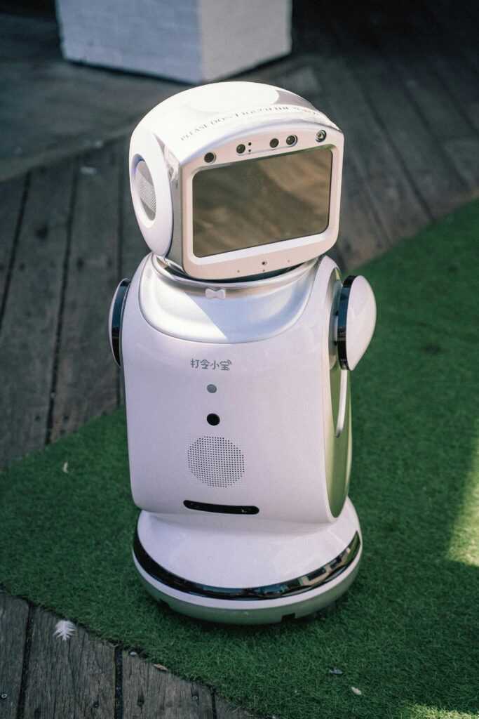 A modern robot stands on grass and wooden flooring, showcasing cutting-edge technology.